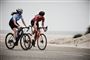 To kvinder cykler ved en strand