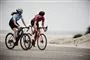 To kvinder cykler ved en strand