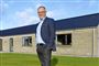 En mand smiler foran et hus