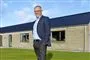 En mand smiler foran et hus
