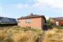 En gammel bungalow med en vild og tør have omkring