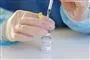 person sidder med glas med coronavaccine