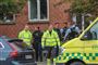 En masse politi og ambulance ved en boligblok.
