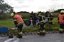 En masse brandmænd ved en væltet bil 