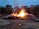 Flere brandmænd arbejder på at slukke flammerne fra hver sin side af et stort brandende bål