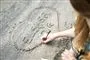 person tegner hjerte i sand