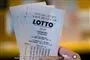 En hånd holder et par Lotto-kuponer.