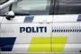 En politibil set fra siden. Den er hvid med blå skrift.