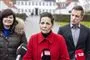 kvinde i rød jakke flankeret af kvinde og mand