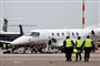 fly i  lufthavn og tre mennesker i gule veste
