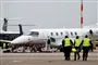fly i  lufthavn og tre mennesker i gule veste
