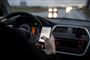 person sidder med mobiltelefon i hånden i bilen