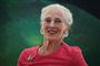 Dronning Margrethe i en koralrød kjole og et stort smil