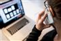 En mand taler i telefon foran en computer