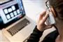 En mand taler i telefon foran en computer