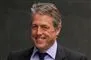 Hugh Grant med et stort smil på vej i retten