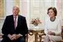 Kong Harald og dronning Sonja sidder ved et guldbord og taler til pressen.