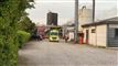 En ambulance og en brandbil i et industriområde med røg