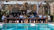Folk ved et langt bord og en pool