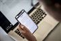 person sidder med mobiltelefon ved tastatur