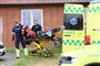 En ambulance og reddere ved et rødt murstenshus.