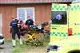 En ambulance og reddere ved et rødt murstenshus.