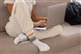 Kvinde i sweatpants sidder i sofa med computer