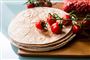 En bunke tortillas ligger på et bord med en klasse tomater ovenpå.