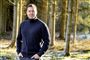 Johannes Langkilde i en skov med et smil og sort vindjakke