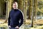 Johannes Langkilde i en skov med et smil og sort vindjakke