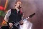Michael Poulsen på scenen han synger ind i en mikrofon. 