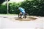 Barn på cykel i vandpyt