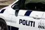 En politibil set fra siden. Den er hvid med blå skrift.