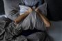 En person krammer en pude over sit ansigt