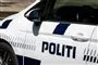 En politibil set fra siden. Den er hvid med blå skrift.