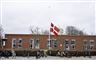 en flagstang med flaget på halv ved en skole