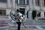 Kvinde bærer cykel op ad trappe