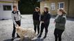 tre kvinder, en mand og en hund på en gårdsplads i solen