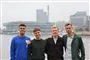4 unge mænd smiler ved en havnefront