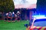 Fire brandmænd står foran den rygende bolig