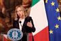den kvindelige premiereminister på en talerstol med det italienske og EU-flag i baggrunden
