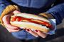 en person holder en hotdog med ketchup på