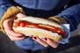 en person holder en hotdog med ketchup på