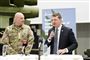 mand i kakkesæt med mikrofin ved siden af mand i militæruniform