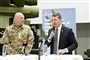 mand i kakkesæt med mikrofin ved siden af mand i militæruniform