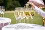 champagne hældes op på glas udenfor i solen