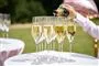 champagne hældes op på glas udenfor i solen