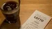 glas med kappe og en lottokupon på et bord