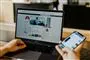 person sidder på facebook på computer og telefon
