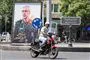 En mand på motorcykel kører forbi plakat med den dræbte iranske stabschef